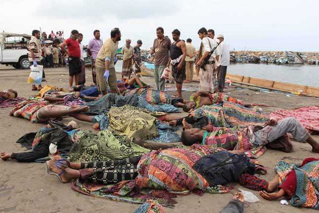 Yemeni police officers check the bodies of Somali refugees, killed in attack by a helicopter while travelling in a vessel off Yemen, at the Red Sea port of Hodeidah, Yemen